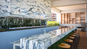 A modern kitchen with a marble countertop, bar stools, and a green wall with plants. - Bright Pier57 Corner Unit Ocean View Romantic Zone (Emiliano Zapata)