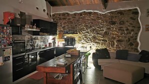 A kitchen with modern appliances, a stone wall, and a cozy seating area with a sofa and ottoman. - B&B Polvere Di Stelle (Trapani)
