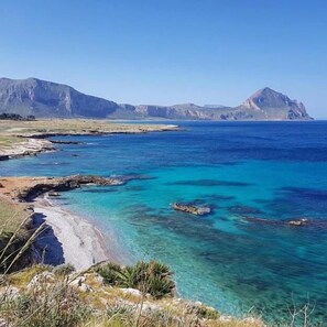 A coastal landscape with clear blue waters, rocky shorelines, and distant mountains. - B&B Polvere Di Stelle (Trapani)