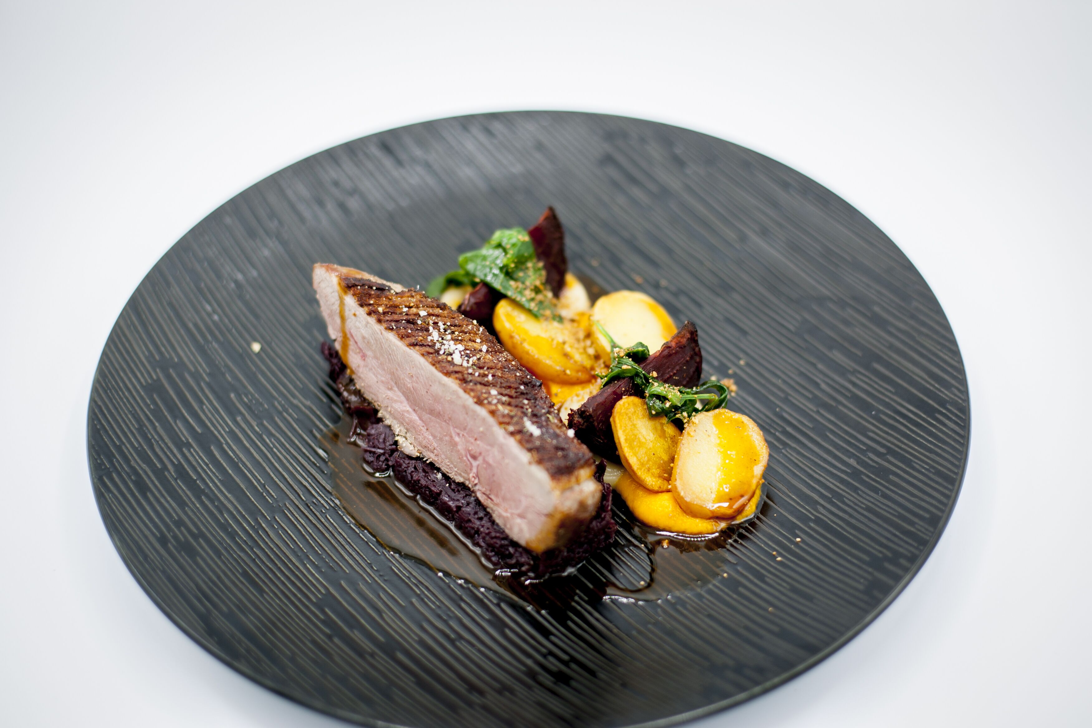 Une assiette contenant un morceau de viande, des légumes et une sauce.