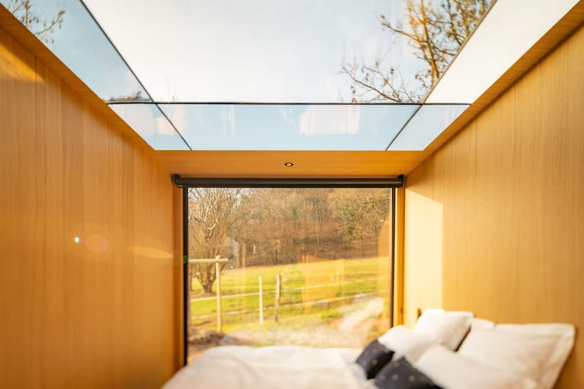 Un dormitorio con cama, almohadas y tragaluz.