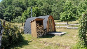 Una cabaña de madera pequeña con techo inclinado, una chimenea y una puerta.