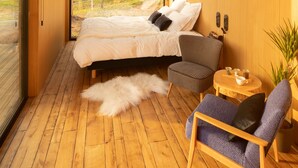 Un dormitorio moderno con una cama grande, un área de descanso y vistas al exterior.