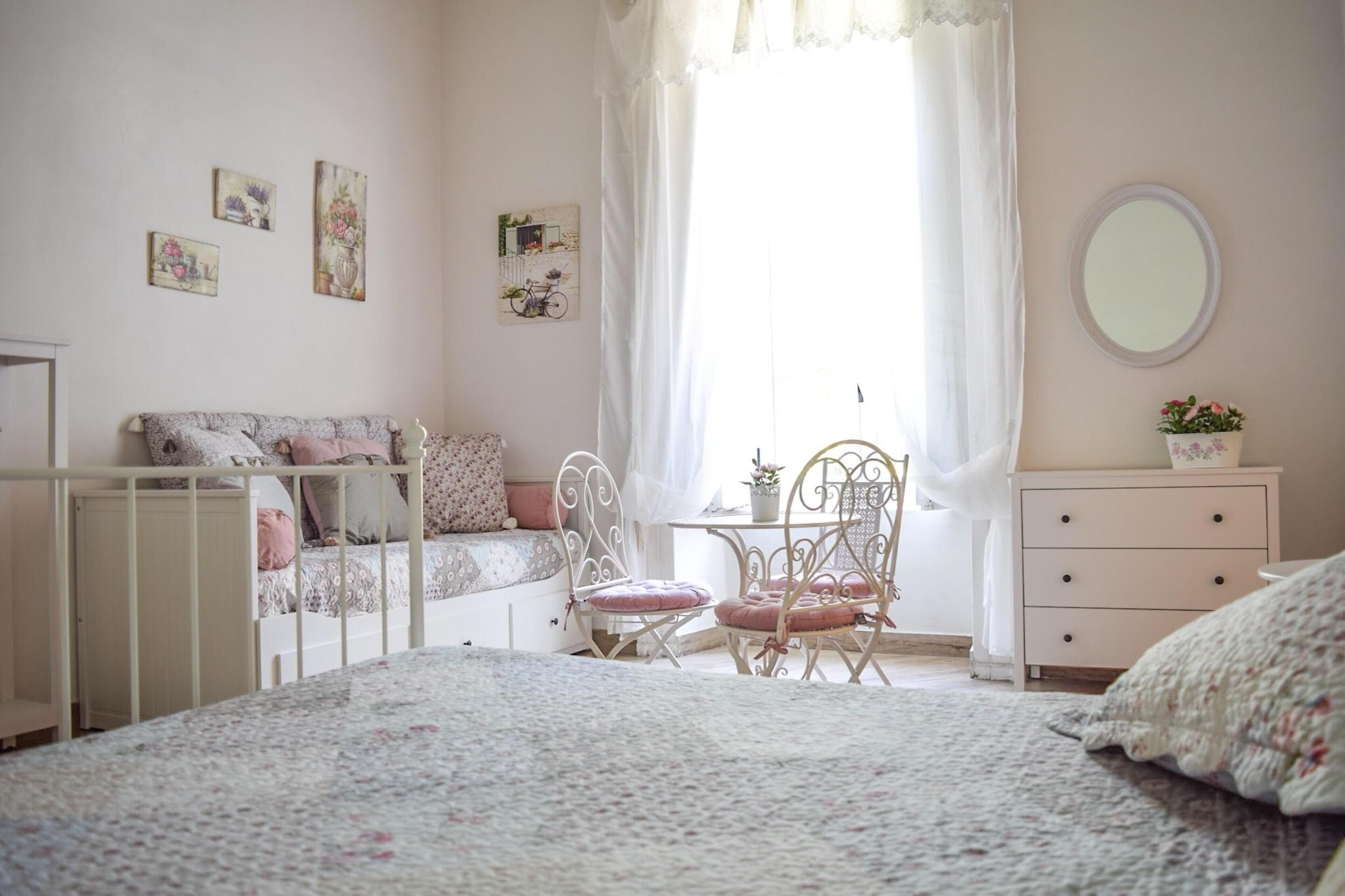 A cozy bedroom with a bed, a chair, a dresser, and a window with curtains.