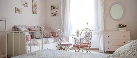 A cozy bedroom with a bed, a chair, a dresser, and a window with curtains.