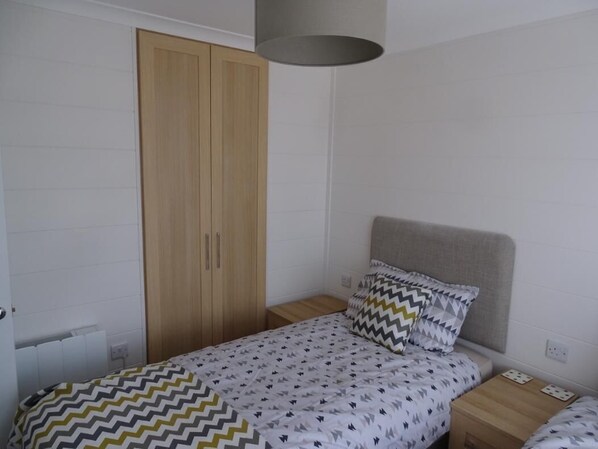 Un dormitorio con una cama, una mesita de noche, un armario y una lámpara.