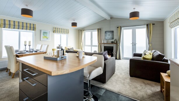 Eine moderne Küche mit Kochinsel, ein Essbereich mit Tisch und Stühlen sowie ein Wohnzimmer mit Sofa und Kamin.