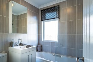 Een bad/douchecombinatie, handdoeken, toiletpapier