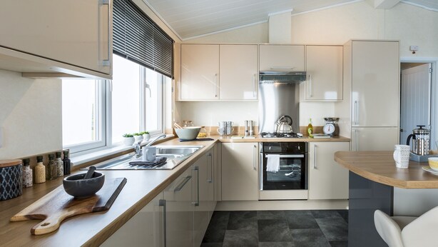 Una cocina moderna con encimera de madera, electrodomésticos de acero inoxidable y una ventana con persianas.