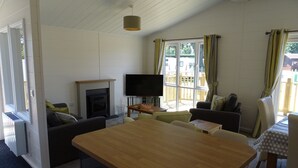 Ein gemütliches Wohnzimmer mit Kamin, Fernseher, Esstisch und Blick ins Freie.