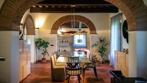 Un espace repas avec une table en verre, des chaises et une arche en briques.