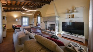 Un salon spacieux doté d’une cheminée, d’un grand téléviseur à écran plat et d’un coin salon confortable.
