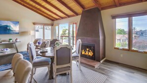 A dining area with a fireplace, wooden ceiling beams, and large windows with a view of the outside. - Ocean 3 Blocks * Prof Design * AC * Upper Level (La Jolla)