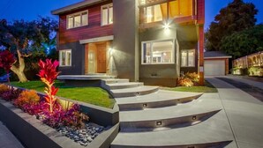 A modern two-story house with a well-lit entrance, a landscaped front yard, and a driveway leading to the garage. - Ocean 3 Blocks * Prof Design * AC * Upper Level (La Jolla)