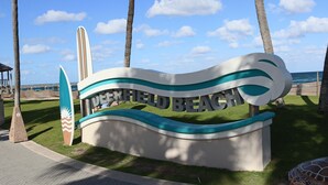 Un letrero de playa con el texto 'Dunder Mifflin Beach' y un diseño de tabla de surf.