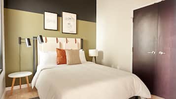A neatly arranged bedroom with a bed, bedside tables, and a wardrobe.