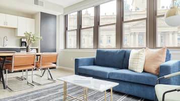 Una sala de estar moderna con un sofá azul, una mesa de centro y un comedor con una mesa y sillas.