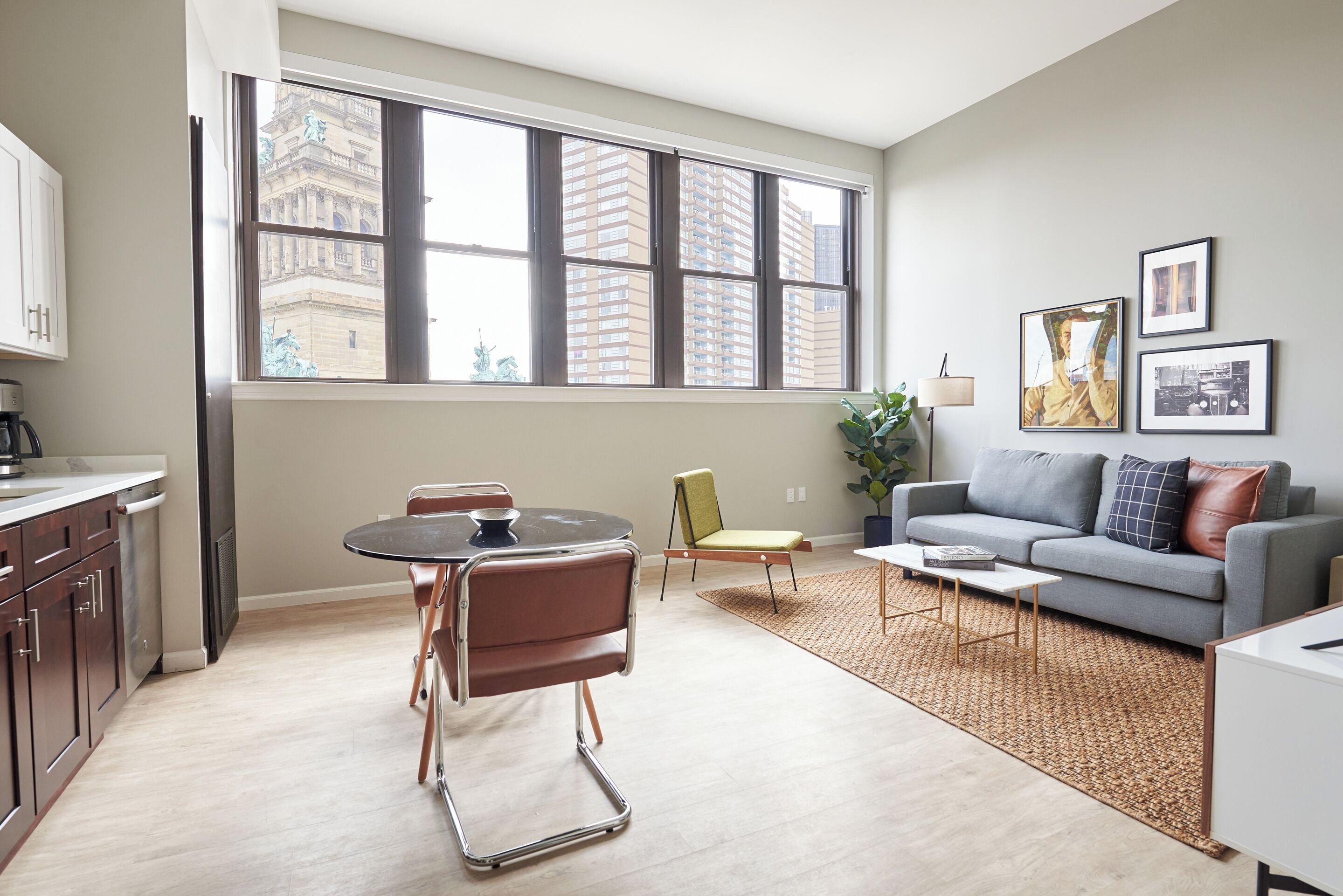 Una sala de estar moderna con comedor, ventanas amplias, un sofá gris y una mesita de centro.