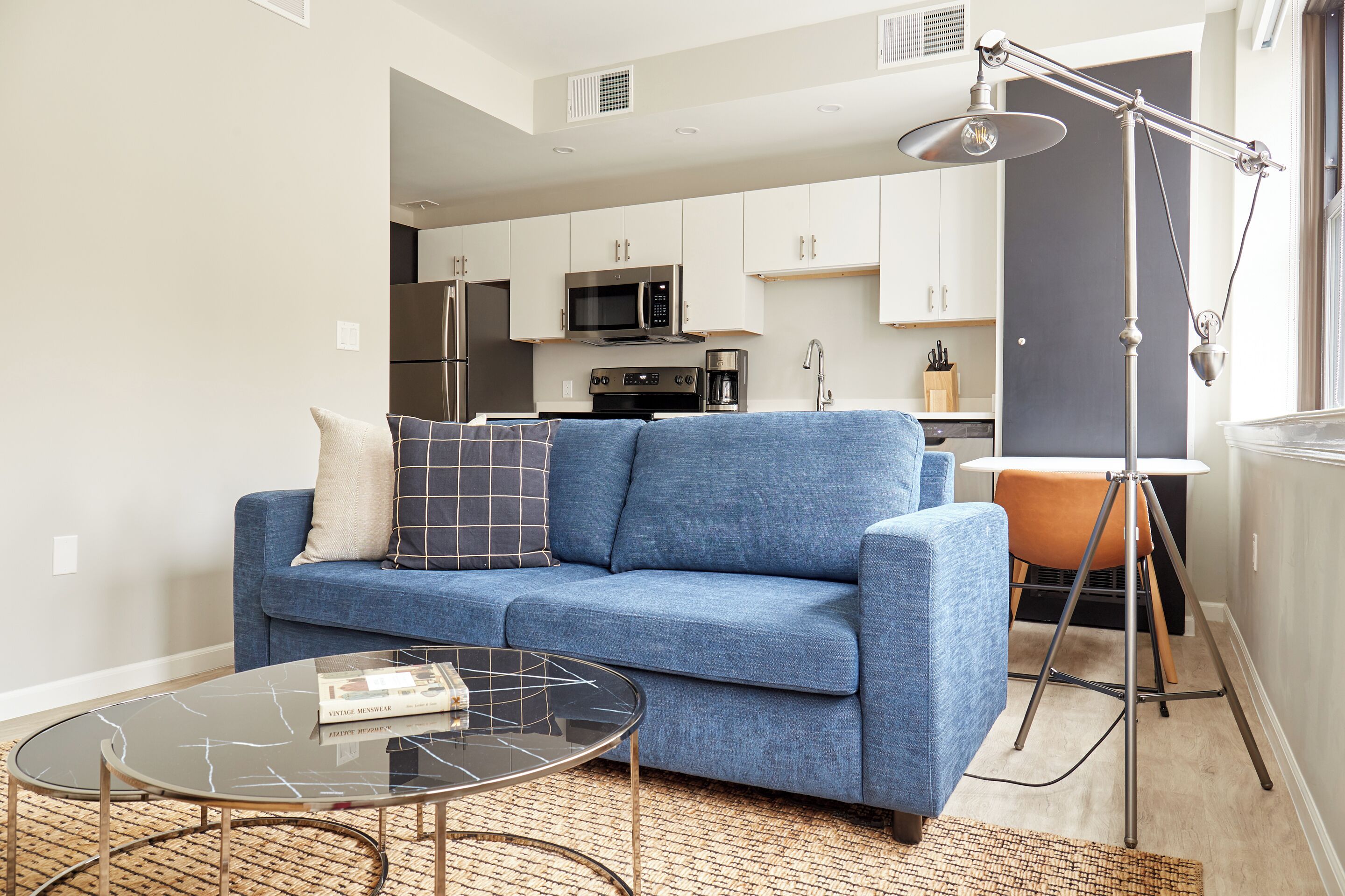 A modern living room with a blue sofa, a glass coffee table, and a floor lamp.