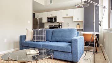 A modern living room with a blue sofa, a glass coffee table, and a floor lamp.