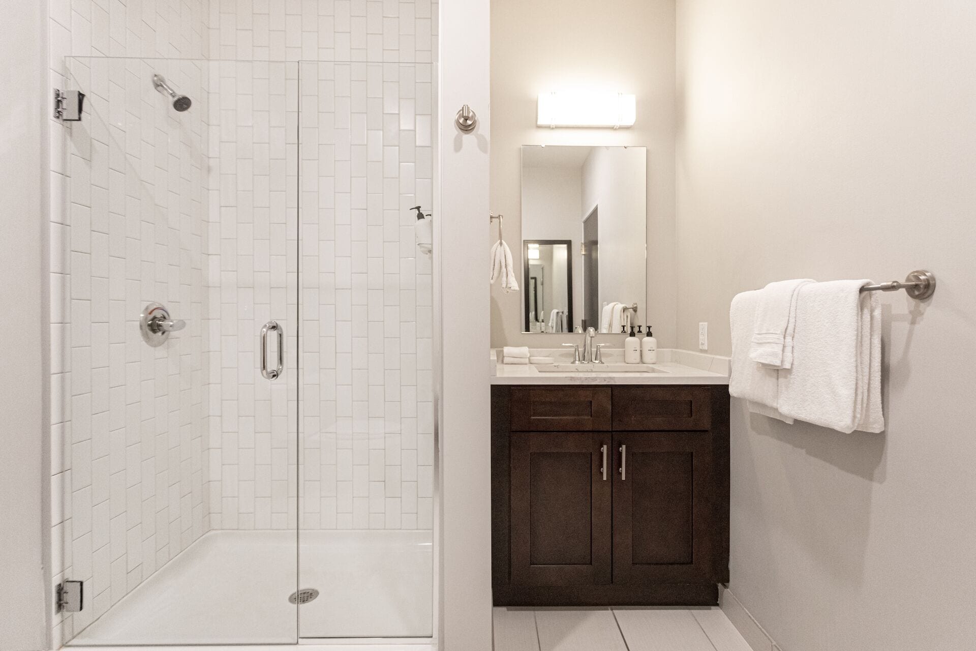 A bathroom with a shower, a sink, a mirror, and a towel rack.