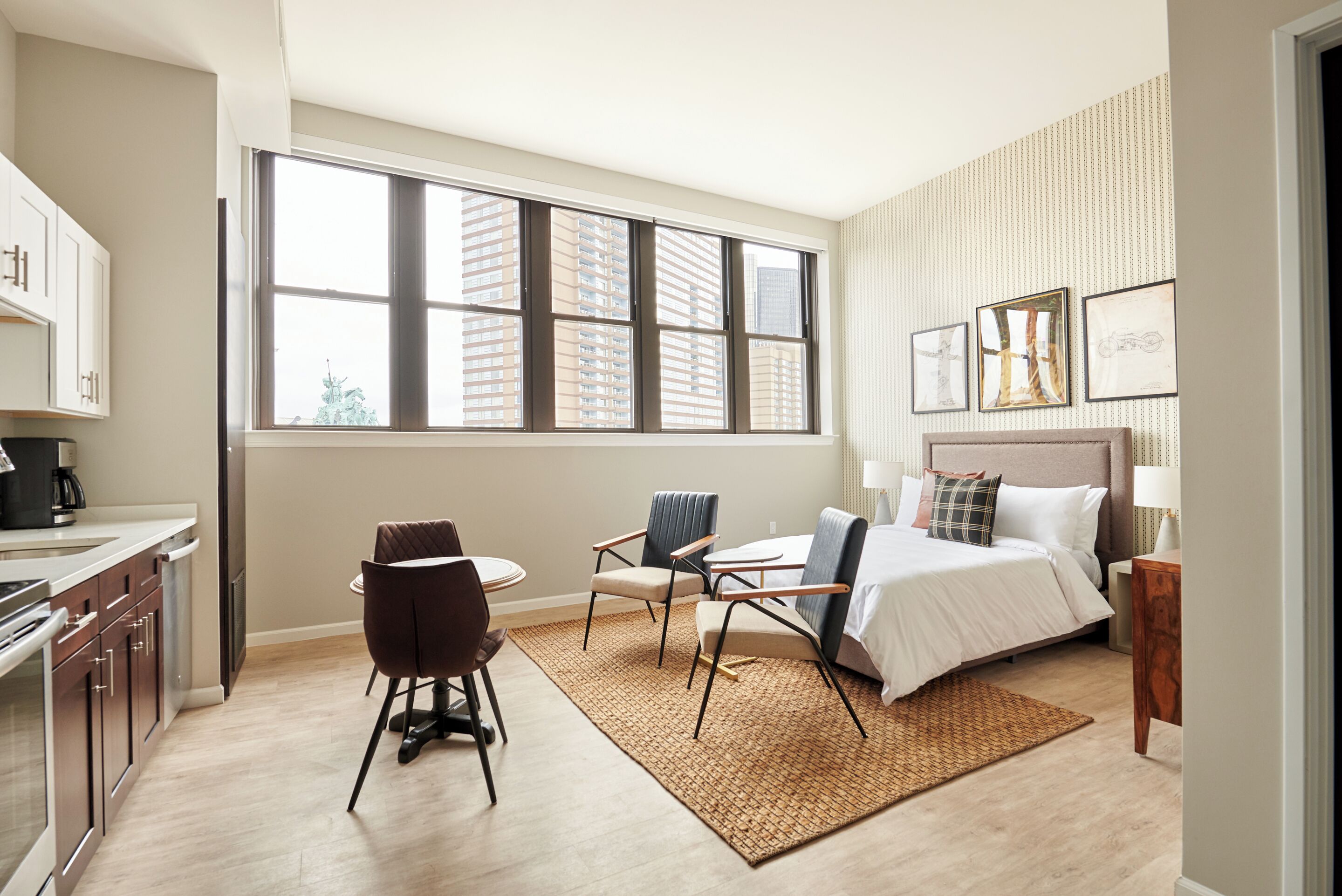 A modern hotel room with a large window, a bed, a desk, and a chair.
