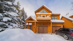 A two-story wooden cabin with a balcony, a garage, and a car parked in front. - Snake River 13 (Keystone)
