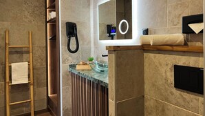 A bathroom with a wooden ladder, a towel rack, a mirror with a light, and a towel on the counter.