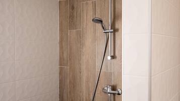 A shower with a handheld showerhead and a wall-mounted faucet.