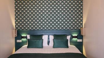 Un lit avec une tête de lit, deux oreillers verts et une couvre-lit à rayures.