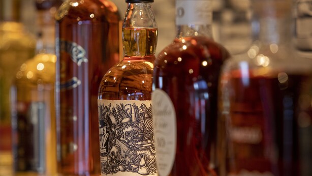 A row of bottles with labels, likely containing alcoholic beverages.