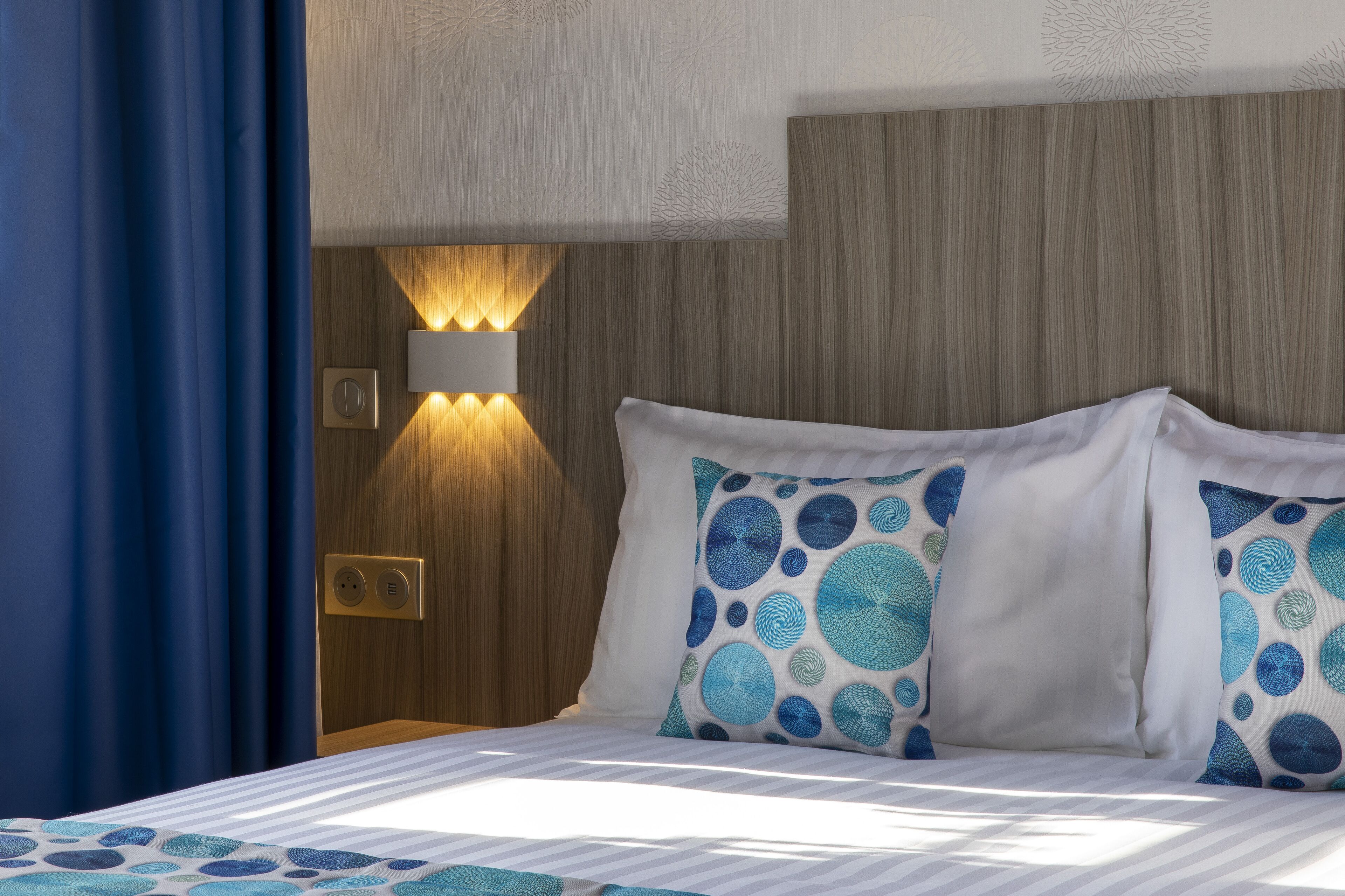 Ein Hotelzimmer mit einem Bett, einer Wandleuchte und einer Steckdose.