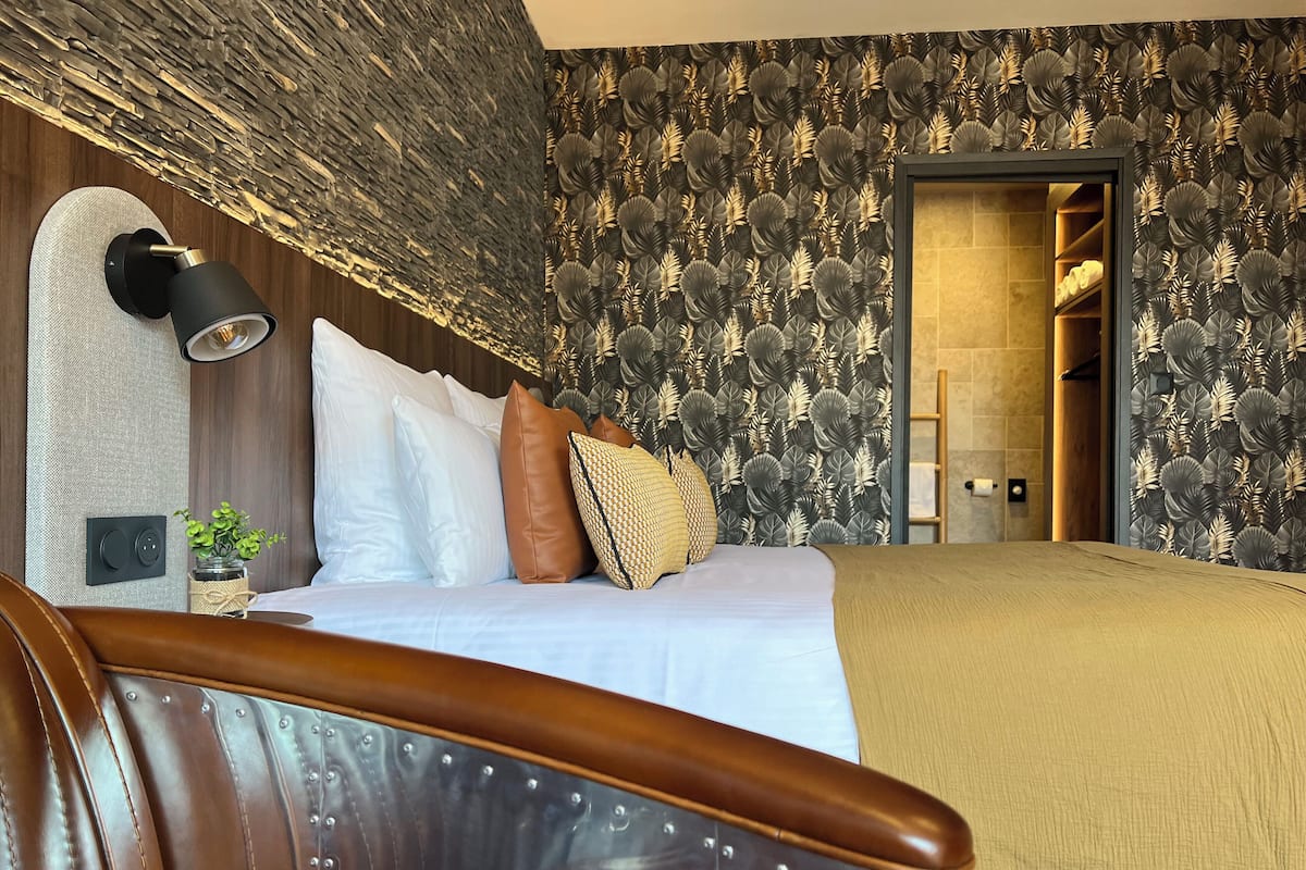 A bedroom with a bed, a nightstand, a lamp, and a wardrobe.