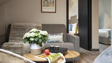 Una sala de estar acogedora con un sofá gris, una mesa de centro de madera con una revista, un jarrón de flores y un cuadro en la pared.