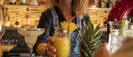A bartender preparing a drink with a pineapple garnish.