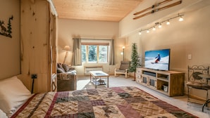 Une pièce confortable avec un grand lit, une télévision, une cheminée et une fenêtre avec des rideaux.
