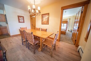 A dining room with a wooden table and chairs, a chandelier, and framed artwork on the walls. - Springs 8819 (Keystone)