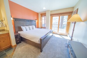 A bedroom with a large bed, a nightstand, a dresser, a window with a view, and a lamp. - Springs 8819 (Keystone)