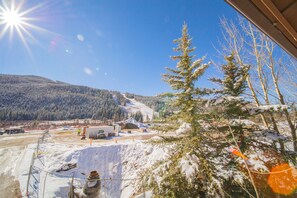 A snowy landscape with a clear sky, a mountain in the background, and a building with a fenced area in the foreground. - Springs 8819 (Keystone)