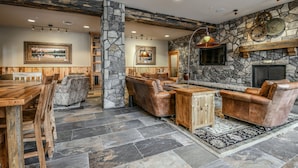A rustic interior with stone walls, leather furniture, and a fireplace.