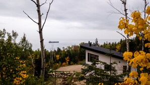 A modern house with a large window, surrounded by trees and a stone wall. - The Arial cottage, spectacular view and Spa (La Malbaie)