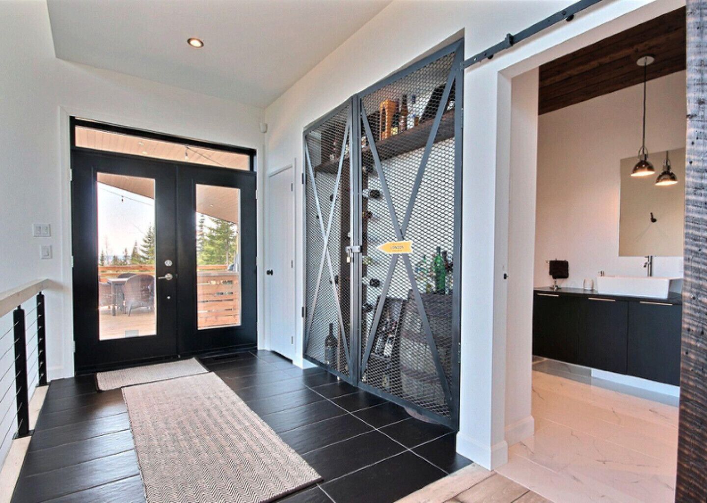 A modern interior with a sliding door leading to a balcony, a kitchen area with dark cabinetry, and a black and white color scheme.