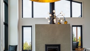 A spacious dining area with a wooden table, a glass bowl centerpiece, and a modern chandelier. - The Arial cottage, spectacular view and Spa (La Malbaie)