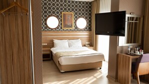 A hotel room with a bed, a desk with a flat-screen TV, two round mirrors, and a wooden headboard. - La Casa Hotel (Kocasinan)