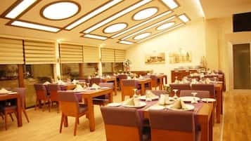 Un comedor con varias mesas y sillas, techo con diseño y vistas al exterior.