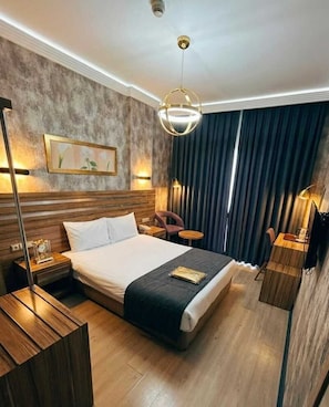 A hotel room with a large bed, bedside tables, a desk, a chair, a lamp, and a painting on the wall. - La Casa Hotel (Kocasinan)
