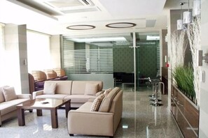 A modern lounge area with a sofa set, a coffee table, and a glass partition separating the seating area from the workspace. - La Casa Hotel (Kocasinan)