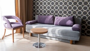 A modern living room with a grey sofa, purple cushions, a wooden coffee table, and a patterned wall. - La Casa Hotel (Kocasinan)