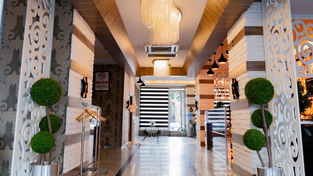 A hotel corridor with a modern design, featuring a chandelier, decorative wall panels, and a seating area with a table and chairs. - La Casa Hotel (Kocasinan)