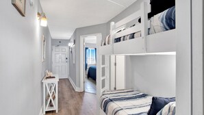 Ett rum med våningssängar, ett litet bord och en dörr som leder till ett annat rum.